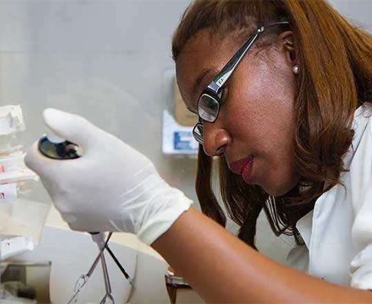 Scientist using a pipette in a biomedical laboratory.