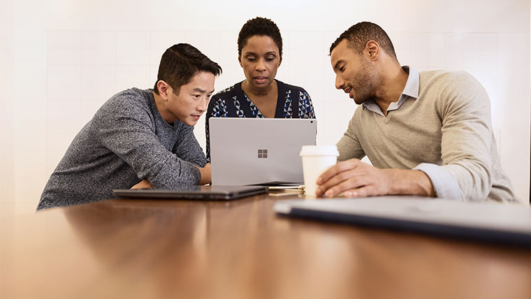 Three persons are having Small conference meeting in modern workspace.