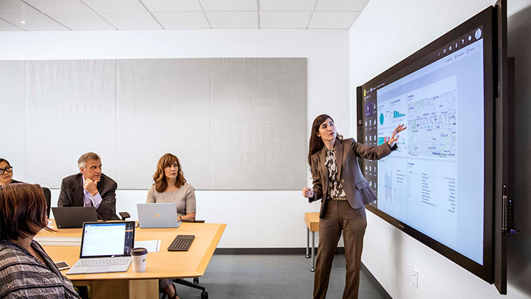 Female businesswoman in suit giving presentation in office conference room.